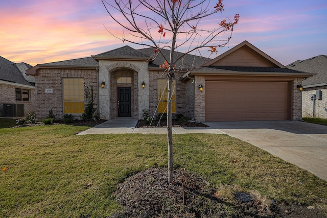 view of front of house featuring a garage, a yard, and central AC