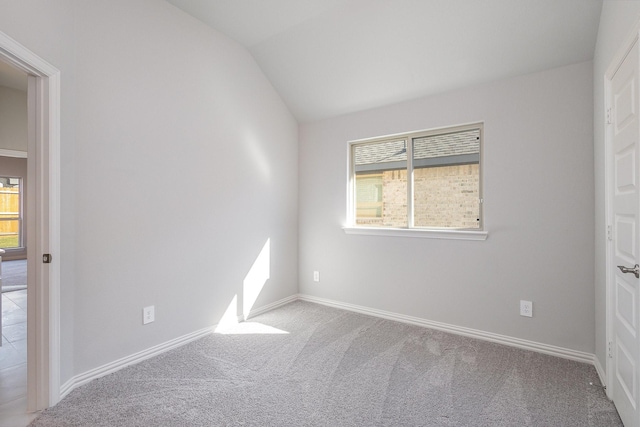 carpeted spare room featuring vaulted ceiling