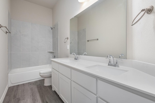 full bathroom featuring vanity, tiled shower / bath combo, wood-type flooring, and toilet