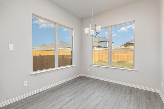 unfurnished dining area featuring a notable chandelier, plenty of natural light, and wood-type flooring