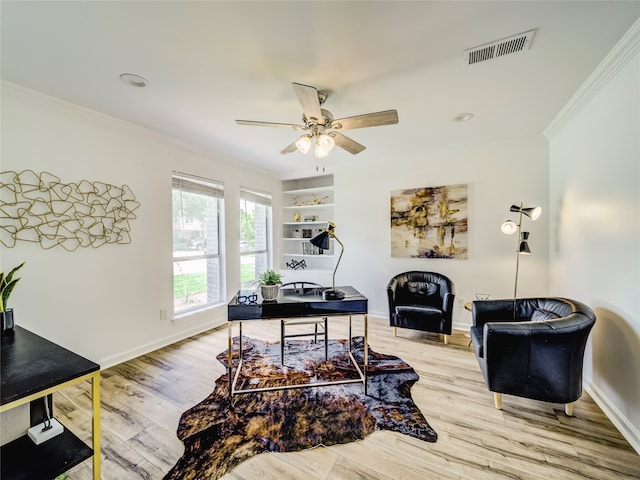 home office with built in shelves, ceiling fan, ornamental molding, and light wood-type flooring