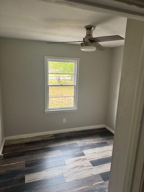 unfurnished room featuring ceiling fan and dark wood-type flooring