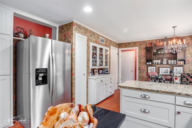 kitchen featuring light stone counters, white cabinetry, stainless steel fridge with ice dispenser, and wallpapered walls