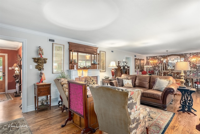 living area with a chandelier, visible vents, crown molding, and wood finished floors