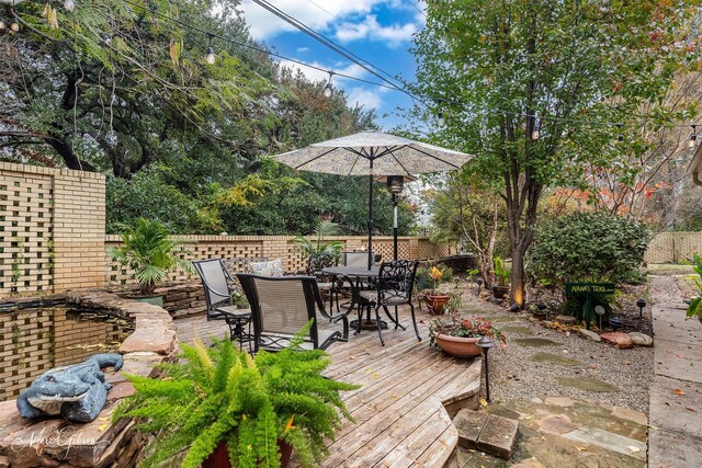 wooden terrace with a fenced backyard and outdoor dining area