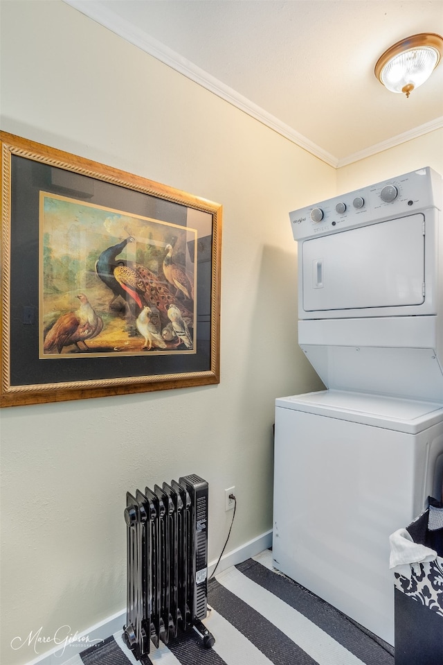 laundry area with ornamental molding, stacked washer / drying machine, laundry area, and baseboards