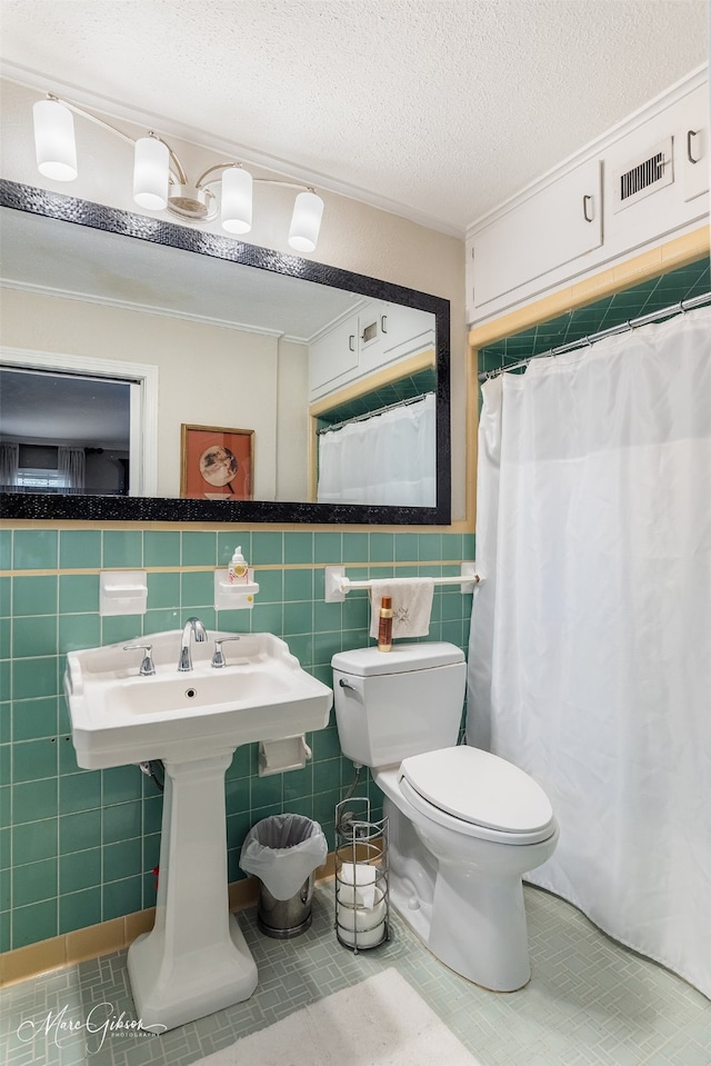 bathroom featuring a textured ceiling, toilet, visible vents, tile walls, and tile patterned floors