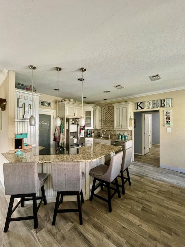 kitchen featuring hanging light fixtures, dark hardwood / wood-style floors, stainless steel fridge, a textured ceiling, and kitchen peninsula