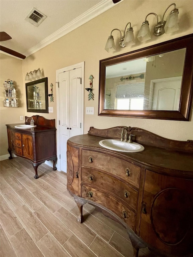 bathroom with hardwood / wood-style floors, vanity, a textured ceiling, and crown molding