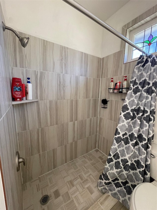 bathroom featuring toilet, curtained shower, and tile walls