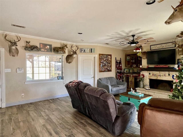 living room with ceiling fan, a fireplace, ornamental molding, and hardwood / wood-style flooring