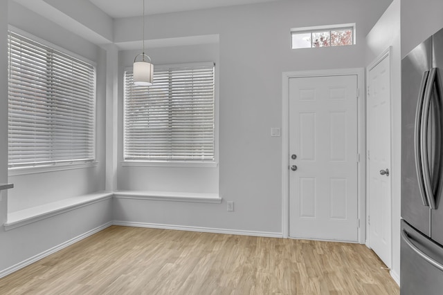 unfurnished dining area featuring baseboards, light wood-style flooring, and a healthy amount of sunlight