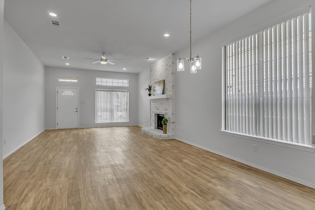 unfurnished living room featuring a fireplace, visible vents, light wood-style flooring, a ceiling fan, and baseboards