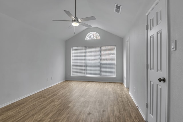 empty room with baseboards, visible vents, a ceiling fan, wood finished floors, and vaulted ceiling