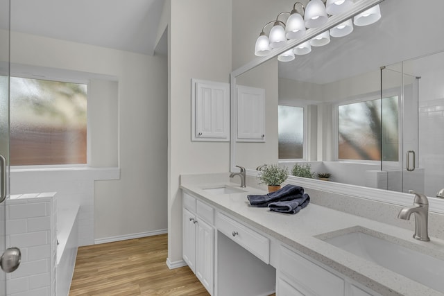 full bath with a stall shower, wood finished floors, a sink, and double vanity