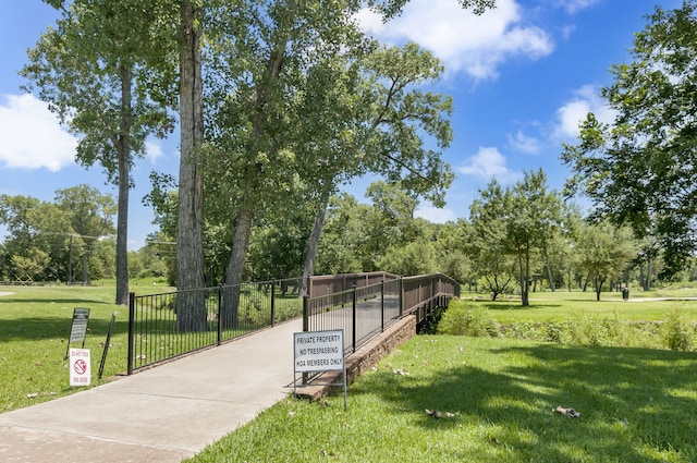 view of community featuring a lawn and fence