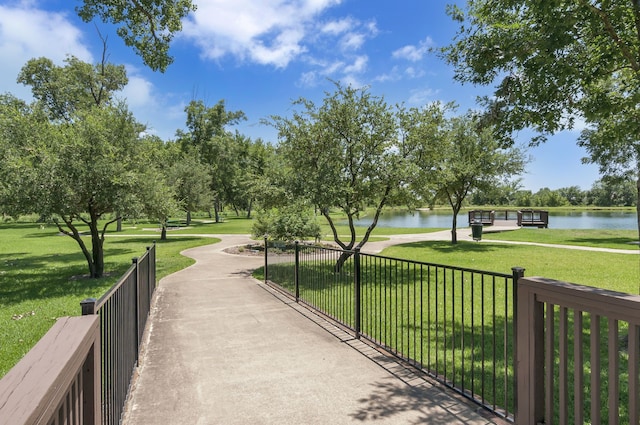 surrounding community featuring a water view, a lawn, and fence