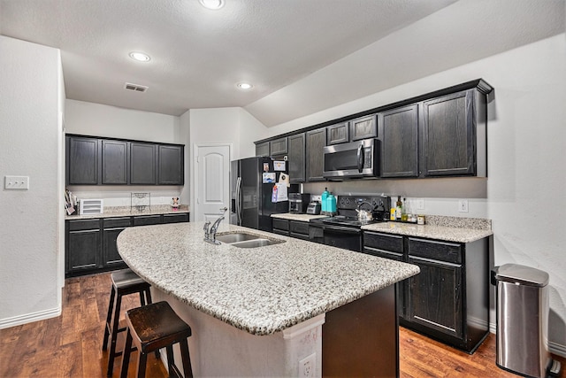 kitchen featuring black appliances, dark hardwood / wood-style flooring, a center island with sink, and sink