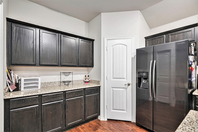 kitchen with light stone countertops, dark hardwood / wood-style flooring, refrigerator with ice dispenser, and lofted ceiling