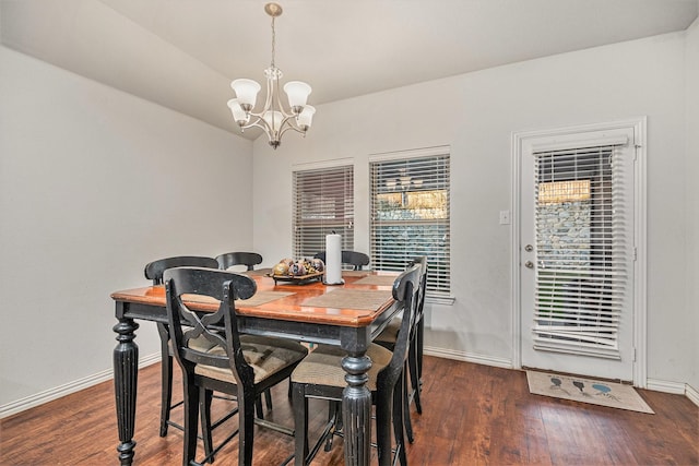 dining area featuring dark wood-type flooring and an inviting chandelier