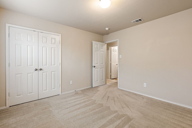 unfurnished bedroom featuring a closet and light colored carpet