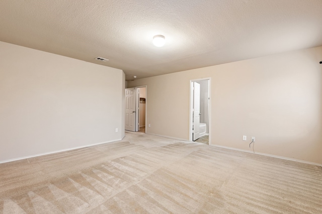 spare room with a textured ceiling and light colored carpet