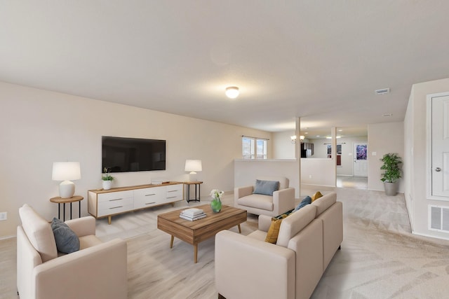 living room featuring light colored carpet and an inviting chandelier