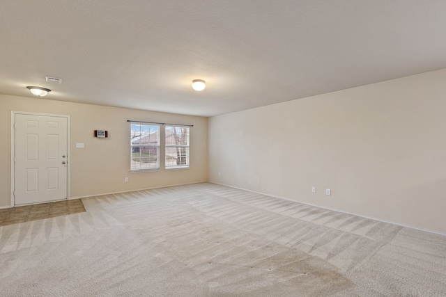 spare room featuring a textured ceiling and light colored carpet