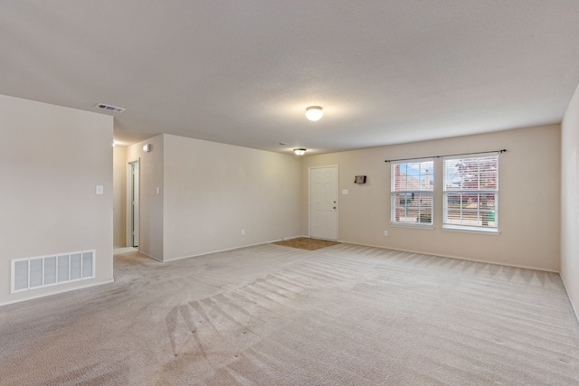 empty room featuring light carpet and a textured ceiling