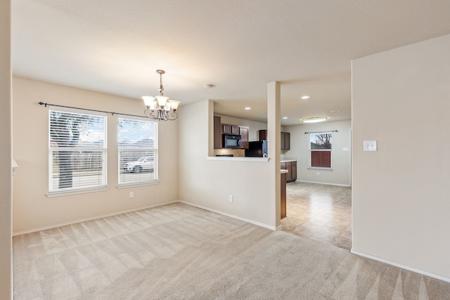 unfurnished room featuring light colored carpet and a chandelier