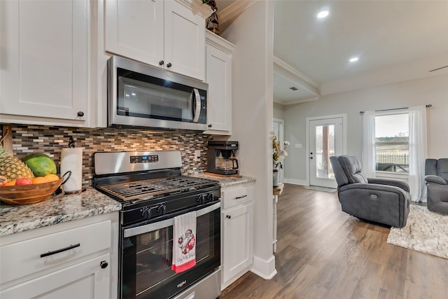 kitchen with white cabinetry, tasteful backsplash, light hardwood / wood-style floors, appliances with stainless steel finishes, and ornamental molding