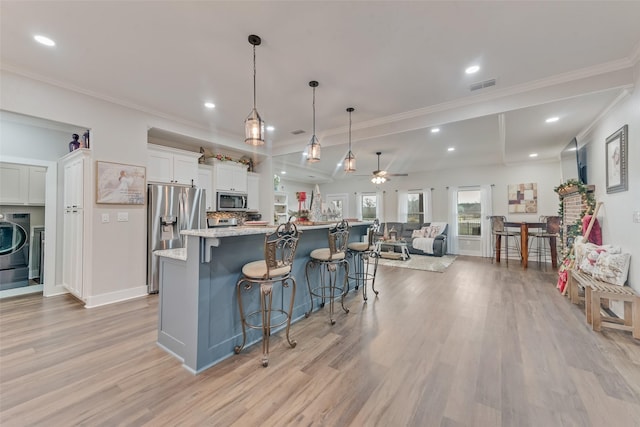 kitchen with stainless steel appliances, ceiling fan, white cabinetry, hanging light fixtures, and a large island