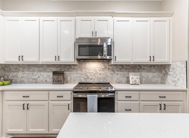 kitchen featuring white cabinets, appliances with stainless steel finishes, and tasteful backsplash