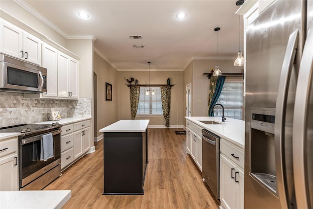 kitchen featuring decorative light fixtures, sink, white cabinetry, and stainless steel appliances