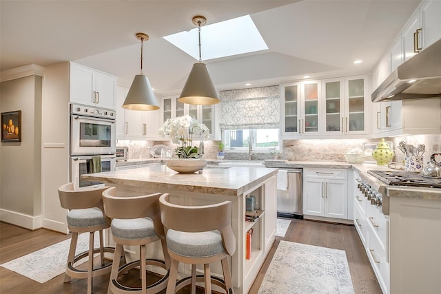 kitchen with light stone countertops, stainless steel appliances, a center island, and white cabinets