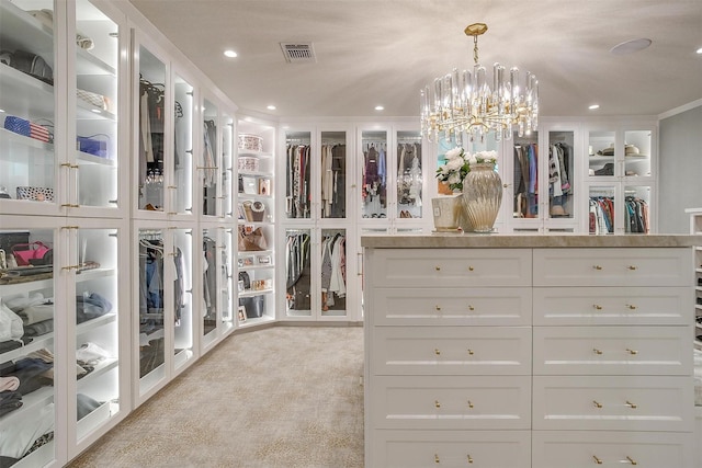 spacious closet with light colored carpet and a chandelier