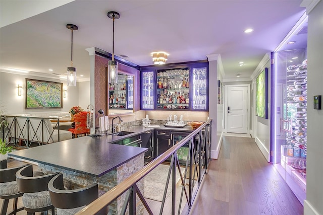 bar with crown molding, decorative light fixtures, sink, and hardwood / wood-style floors