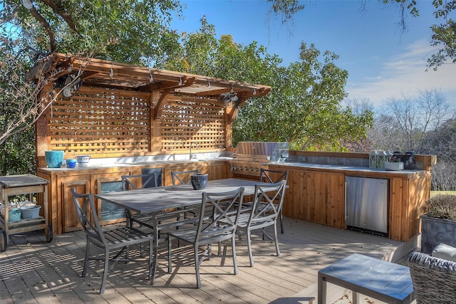 wooden deck featuring exterior kitchen, area for grilling, and a bar