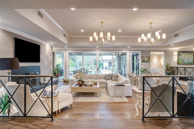 living room featuring hardwood / wood-style flooring, crown molding, an inviting chandelier, and a tray ceiling