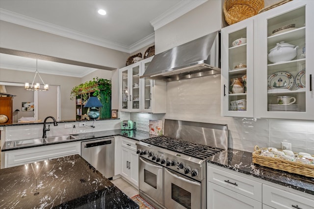 kitchen with pendant lighting, dark stone counters, wall chimney range hood, appliances with stainless steel finishes, and white cabinetry