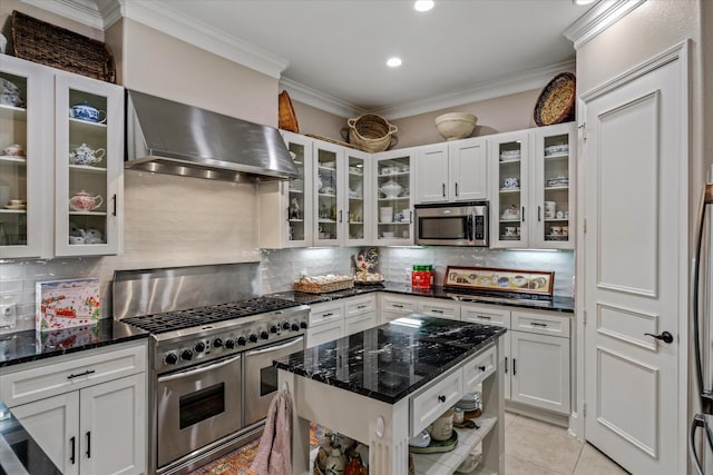 kitchen with stainless steel appliances, wall chimney range hood, white cabinets, and dark stone counters