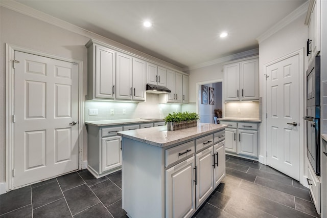 kitchen featuring backsplash, crown molding, black appliances, white cabinets, and a center island