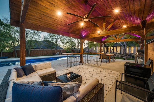 patio terrace at dusk with a fenced in pool, outdoor lounge area, a mountain view, and an outbuilding