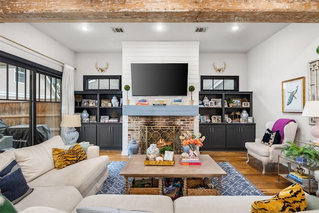 living room featuring beam ceiling, a fireplace, and light hardwood / wood-style floors