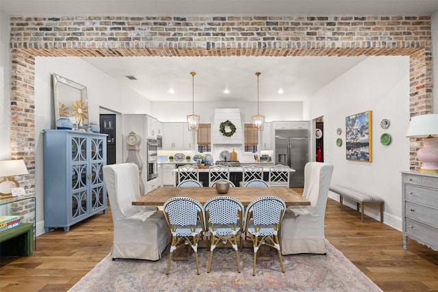 dining room with brick wall and light wood-type flooring