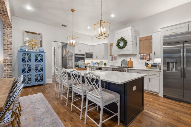 kitchen with white cabinetry, a kitchen island, a kitchen breakfast bar, and appliances with stainless steel finishes