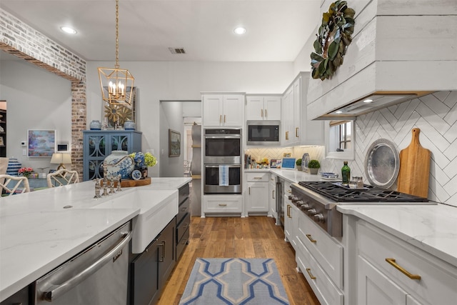 kitchen featuring pendant lighting, stainless steel appliances, light hardwood / wood-style floors, and white cabinets