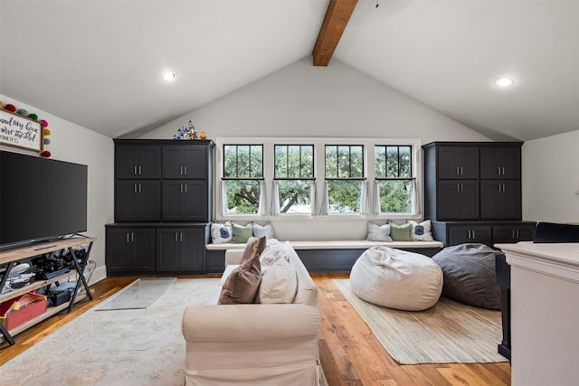 living room with light hardwood / wood-style floors and vaulted ceiling with beams