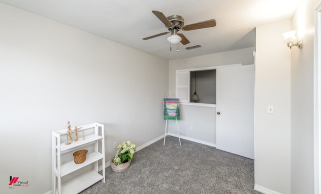 interior space featuring ceiling fan, carpet, and a textured ceiling