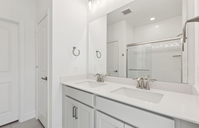 bathroom featuring tile patterned flooring, a shower with shower door, and vanity